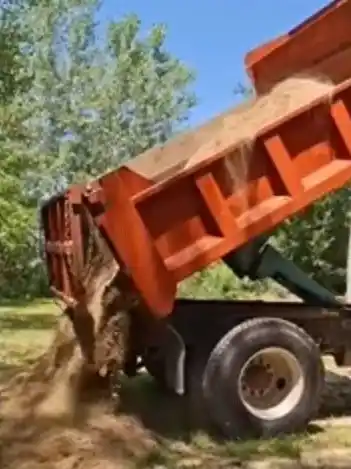 Kenny D's dump truck unloading material at a local job site
