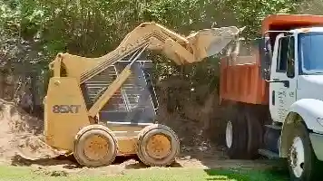 Skid loader loading material into Kenny D's dump truck on a local job